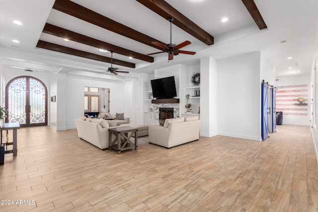 living room with beam ceiling, light hardwood / wood-style floors, a fireplace, and french doors