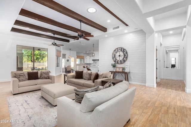 living room featuring beamed ceiling, ceiling fan, light hardwood / wood-style floors, and wooden walls