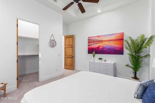 bedroom featuring a walk in closet, ceiling fan, a closet, and light colored carpet