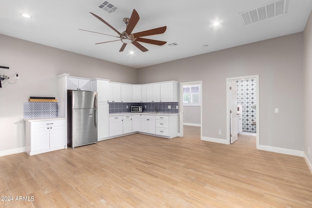 kitchen featuring appliances with stainless steel finishes, backsplash, ceiling fan, white cabinets, and light hardwood / wood-style floors