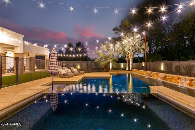 pool at dusk featuring a patio area and pool water feature