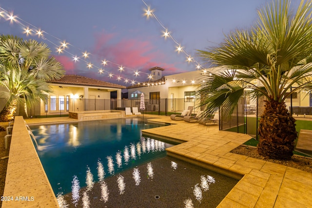 pool at dusk with a patio area