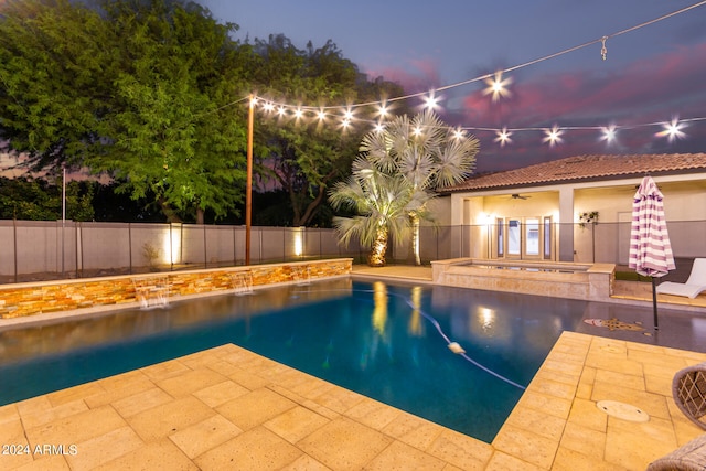 pool at dusk with an in ground hot tub, pool water feature, a patio, and ceiling fan