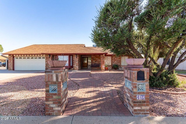 single story home with a garage, driveway, and brick siding