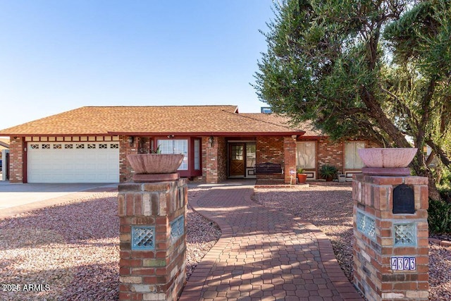 single story home featuring a garage, driveway, brick siding, and roof with shingles