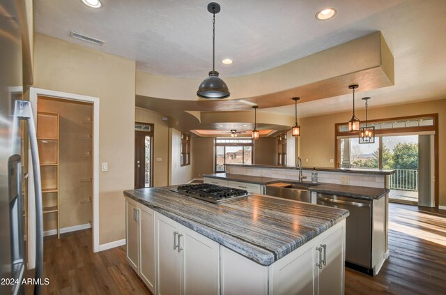 kitchen with a center island, dark wood-type flooring, sink, appliances with stainless steel finishes, and white cabinetry