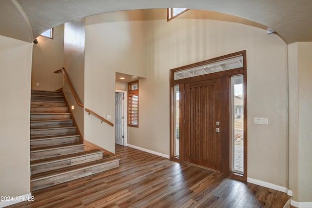 foyer entrance with hardwood / wood-style floors and a towering ceiling