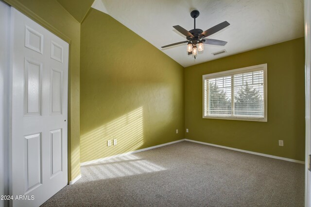 carpeted empty room with vaulted ceiling and ceiling fan