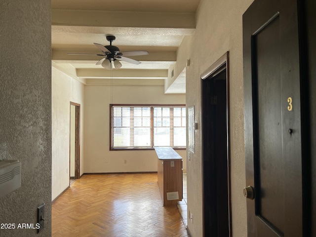 corridor featuring a textured ceiling, a textured wall, visible vents, baseboards, and beamed ceiling