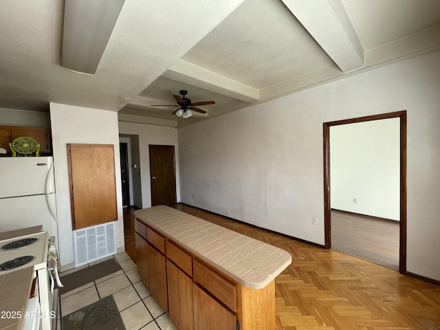 kitchen with white appliances, visible vents, tile countertops, ceiling fan, and beamed ceiling