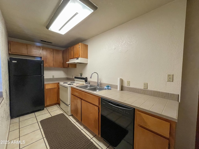 kitchen featuring visible vents, brown cabinets, under cabinet range hood, black appliances, and a sink