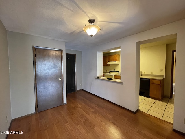 empty room featuring a textured ceiling, light wood finished floors, and baseboards