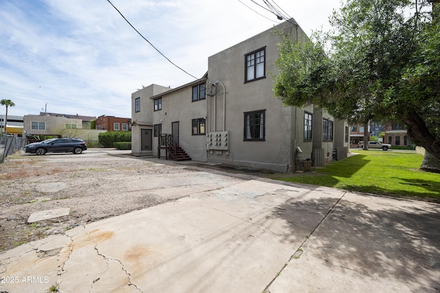 rear view of property featuring a lawn and stucco siding