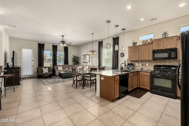 kitchen featuring sink, light tile patterned floors, kitchen peninsula, hanging light fixtures, and black appliances