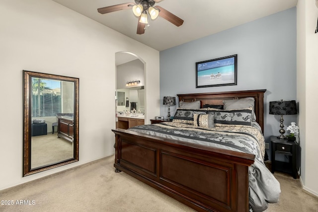 bedroom featuring ceiling fan, light colored carpet, connected bathroom, and vaulted ceiling