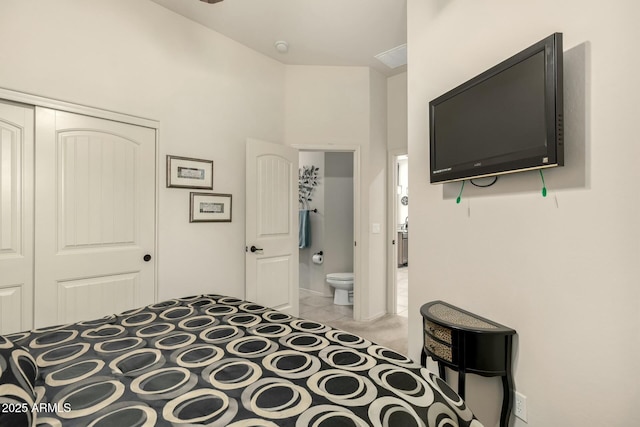 carpeted bedroom with ensuite bathroom and a closet