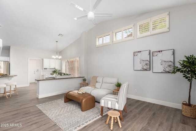 living area with visible vents, baseboards, wood finished floors, high vaulted ceiling, and ceiling fan with notable chandelier