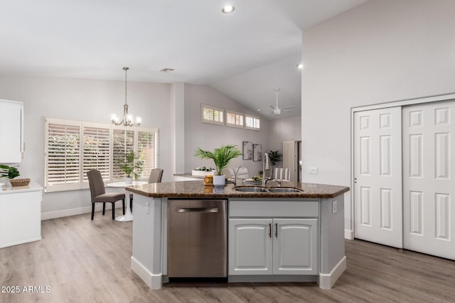 kitchen with lofted ceiling, stainless steel dishwasher, light wood-style floors, white cabinets, and a sink