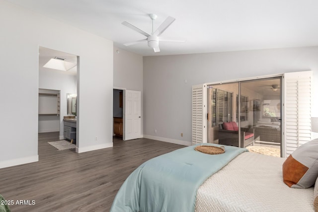 bedroom featuring dark wood-style floors, baseboards, vaulted ceiling, and ensuite bath