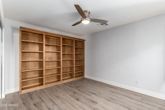 empty room featuring light wood-style flooring, a ceiling fan, visible vents, and baseboards