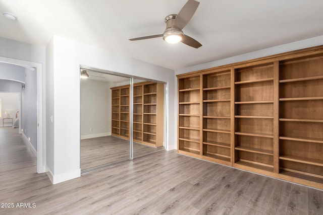 interior space with light wood-style flooring, baseboards, arched walkways, and a closet