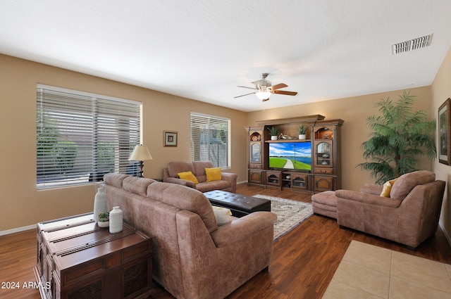 living area featuring dark wood-type flooring, visible vents, baseboards, and a ceiling fan