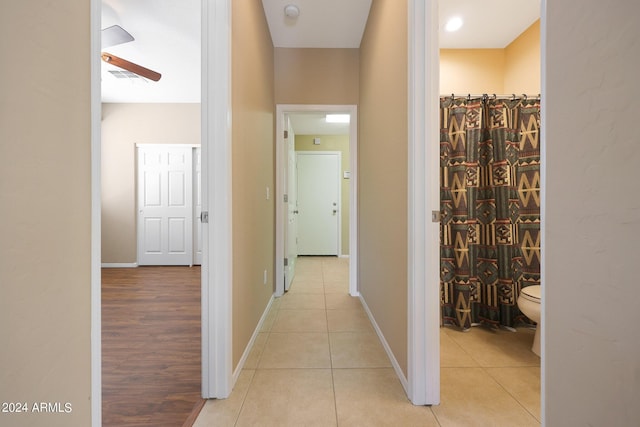 corridor featuring light tile patterned floors, visible vents, and baseboards