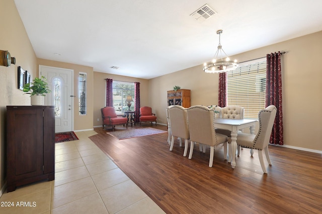 dining space featuring light wood-style flooring, visible vents, a chandelier, and baseboards