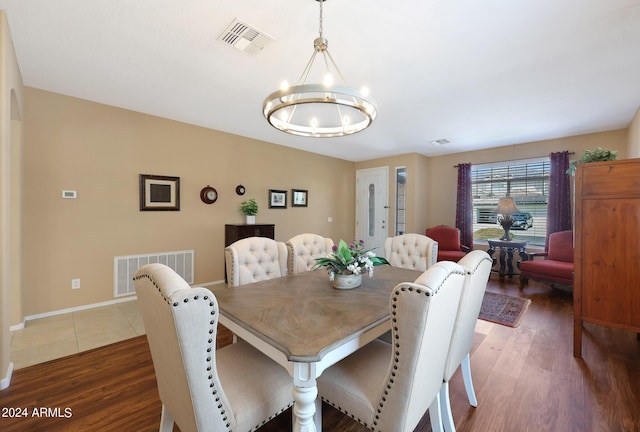 dining space featuring baseboards, dark wood-type flooring, visible vents, and a notable chandelier