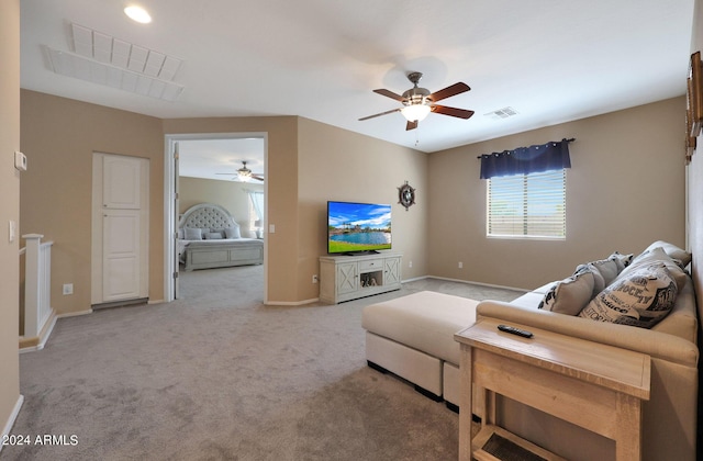 living area with light carpet, baseboards, visible vents, and ceiling fan