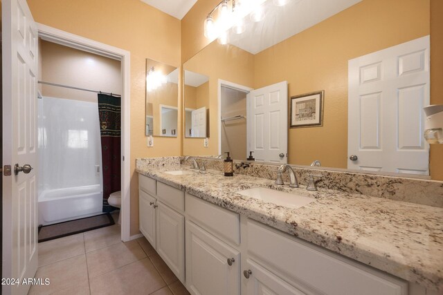 bathroom with double vanity, a sink, toilet, and tile patterned floors