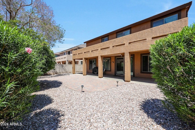 rear view of property with a patio area, fence, and stucco siding