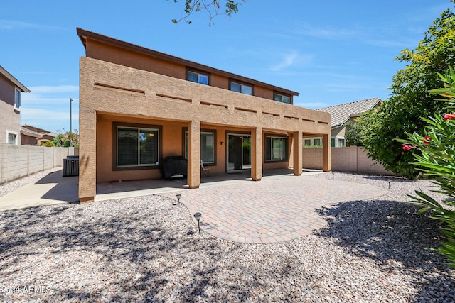 back of property with stucco siding, a fenced backyard, central AC, and a patio