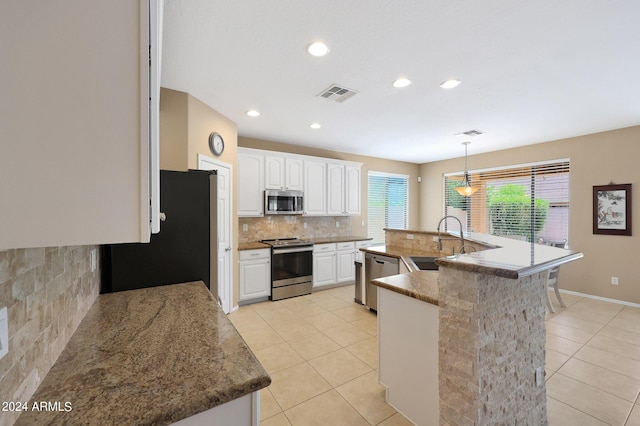 kitchen featuring light tile patterned flooring, white cabinetry, appliances with stainless steel finishes, an island with sink, and pendant lighting