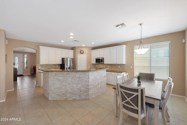 kitchen with pendant lighting, stainless steel appliances, visible vents, white cabinets, and a kitchen island