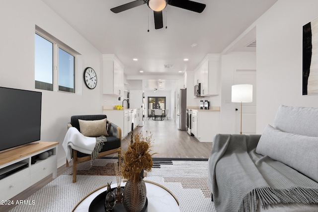 living room with sink, ceiling fan, and light wood-type flooring