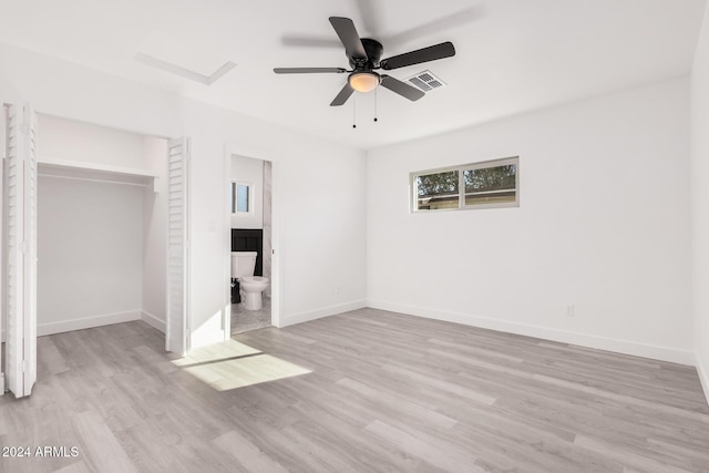 unfurnished bedroom with light wood-type flooring, ensuite bath, ceiling fan, and a closet