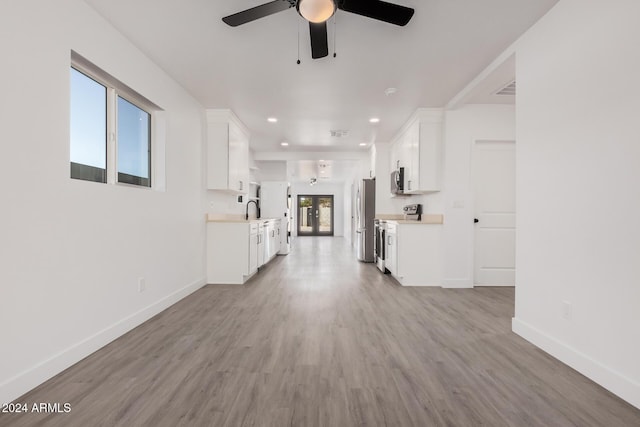 unfurnished living room with sink, a wealth of natural light, light hardwood / wood-style floors, and ceiling fan