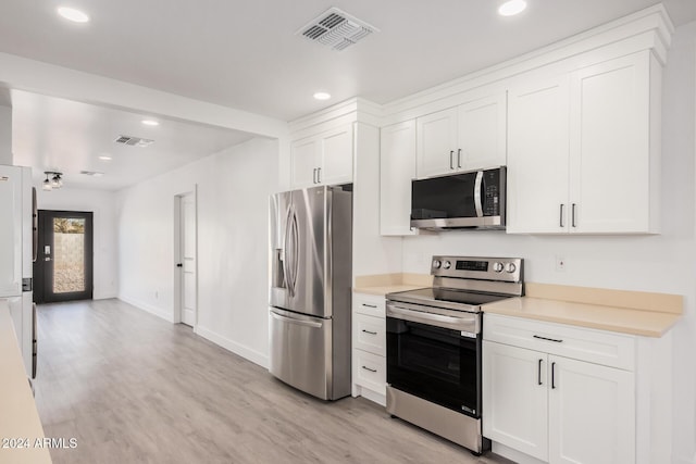 kitchen with stainless steel appliances, white cabinets, and light wood-type flooring