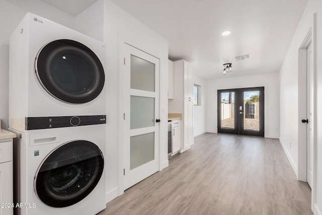 laundry room featuring french doors, stacked washer and dryer, and light wood-type flooring