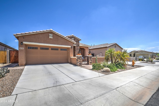 mediterranean / spanish-style house featuring a fenced front yard, a tile roof, driveway, a gate, and stucco siding