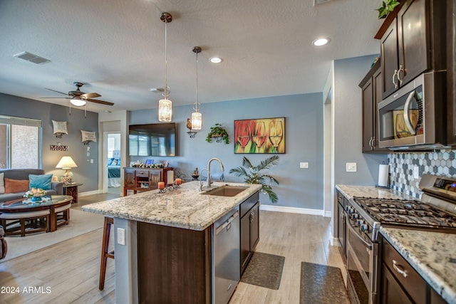 kitchen featuring light wood finished floors, visible vents, appliances with stainless steel finishes, dark brown cabinets, and a sink