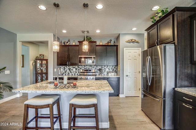 kitchen with stainless steel appliances, tasteful backsplash, a sink, and dark brown cabinets