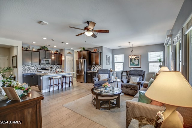 living room with a ceiling fan, recessed lighting, and light wood-style flooring