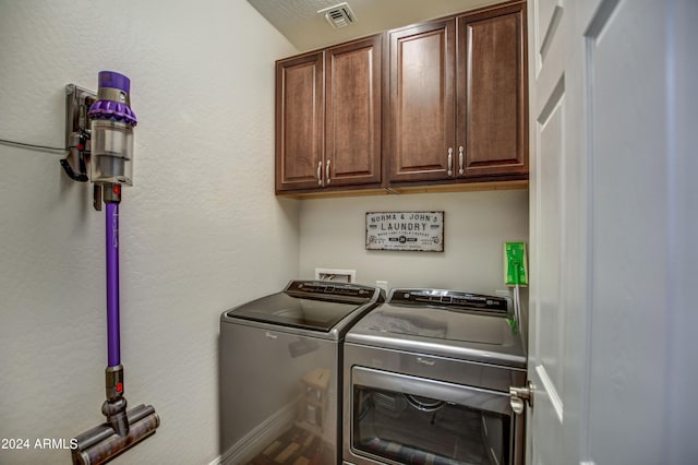 washroom featuring baseboards, visible vents, cabinet space, and washing machine and clothes dryer