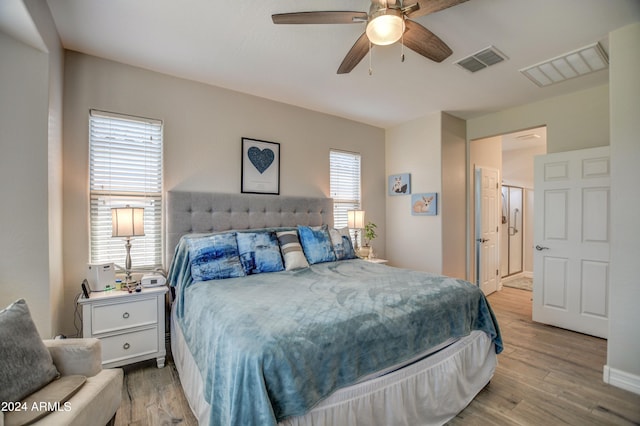 bedroom featuring a ceiling fan, visible vents, and wood finished floors