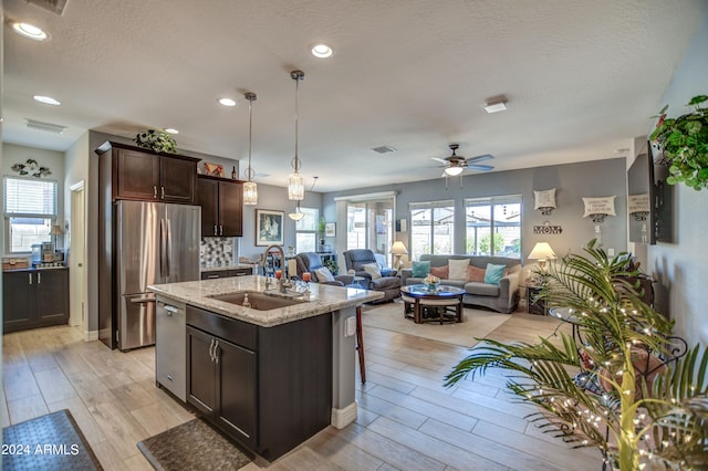 kitchen featuring stainless steel appliances, visible vents, light wood-style floors, a sink, and dark brown cabinetry