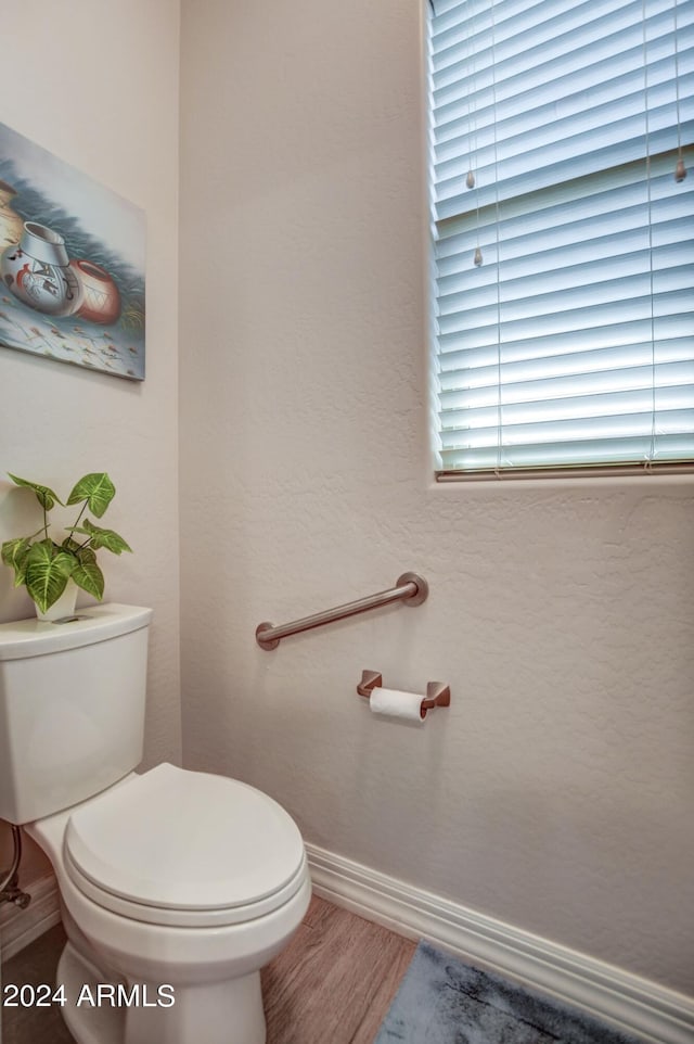 bathroom with wood finished floors, toilet, and baseboards