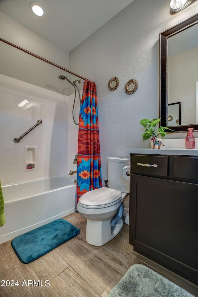 full bath featuring shower / bath combo, a textured wall, toilet, wood finished floors, and vanity