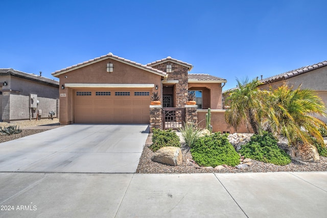 view of front of home with stucco siding, an attached garage, stone siding, driveway, and a tiled roof